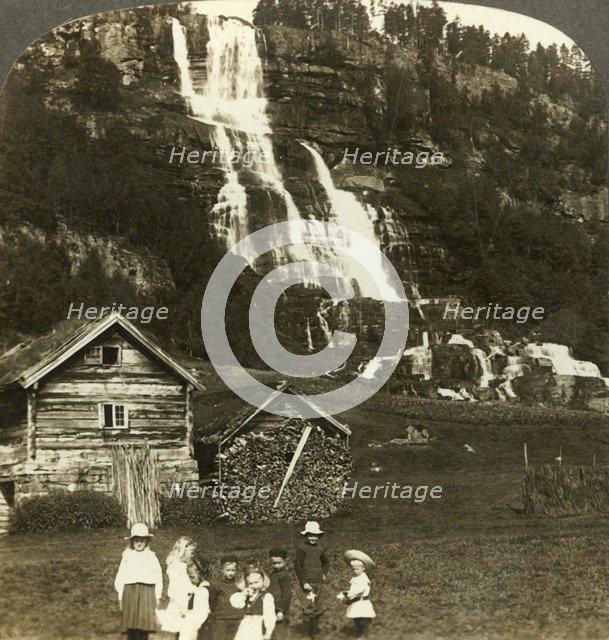 'Children at play in a farmer's field with terraced Tvinde waterfall, Vossevangen, Norway', c1905. Creator: Unknown.