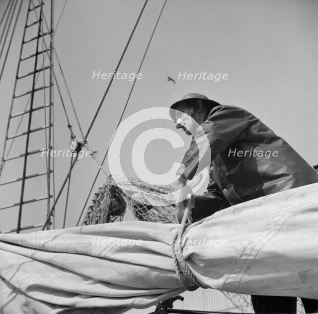 Possibly:  A New England fisherman preparing his boat to leave the New York docks, 1943. Creator: Gordon Parks.
