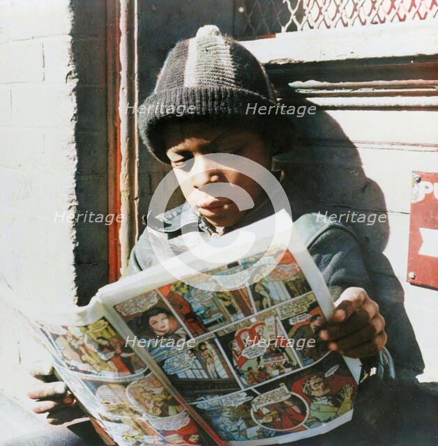 Negro youth reading a funny paper on a door step in the Southwest section, Washington, D.C., 1942. Creator: Gordon Parks.