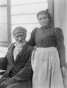 Elderly African American couple posed outside of building, near Hampton Institute..., 1899 or 1900. Creator: Frances Benjamin Johnston.