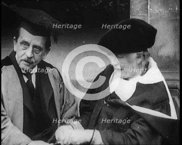 Sir James Barrie and Ellen Terry Sitting Together in Academic Dress Outside St Andrew's Uni, 1922. Creator: British Pathe Ltd.