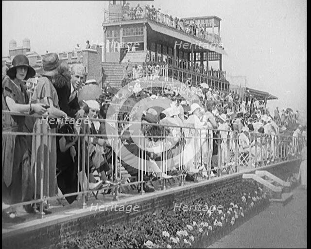 A Large Crowd of Civilians Wearing Smart Outfits and Hats Watching a Horse Race, 1920. Creator: British Pathe Ltd.