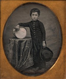 Barefoot Boy Holding Hat and Drum Stick, Leaning Forearm on Child-sized Drum on Table, 1850s. Creator: Unknown.