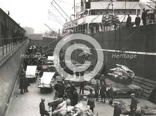 Cargo being loaded or unloaded from a ship, Royal Victoria Dock, Canning Town, London, c1930. Artist: Unknown