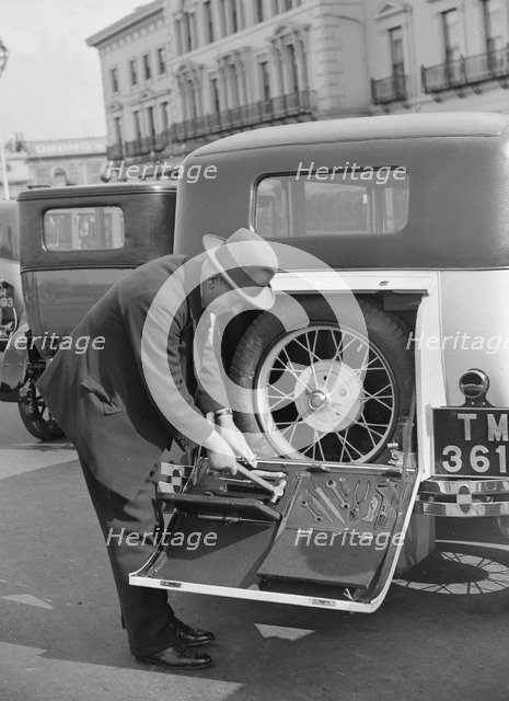 A driver opening the fitted toolkit of his Ford Model A at the Southport Rally, 1928. Artist: Bill Brunell.