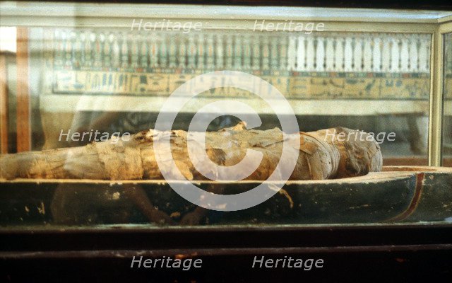 Mummy wrapped in bandages and lying on the base of a coffin, Ancient Egyptian. Artist: Unknown