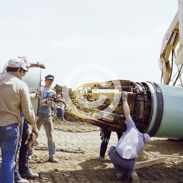 A team of men joining two steel pipes together on the Martin pipeline, Hertfordshire, 07/07/1981. Creator: John Laing plc.