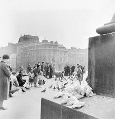 People feeding pigeons in Trafalgar Square, City of Westminster, London, c1950. Artist: Henry Grant