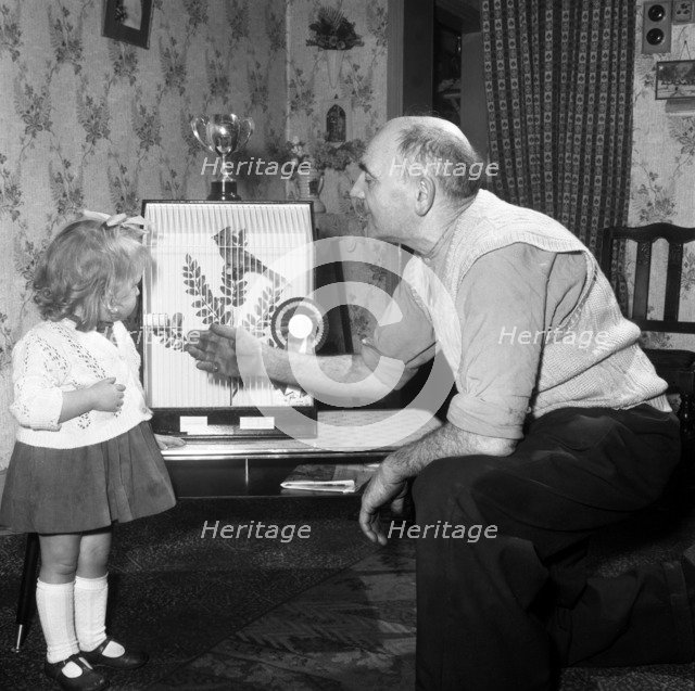 Grandfather and child with a prize winning caged bird, Horden, County Durham, 1963. Artist: Michael Walters