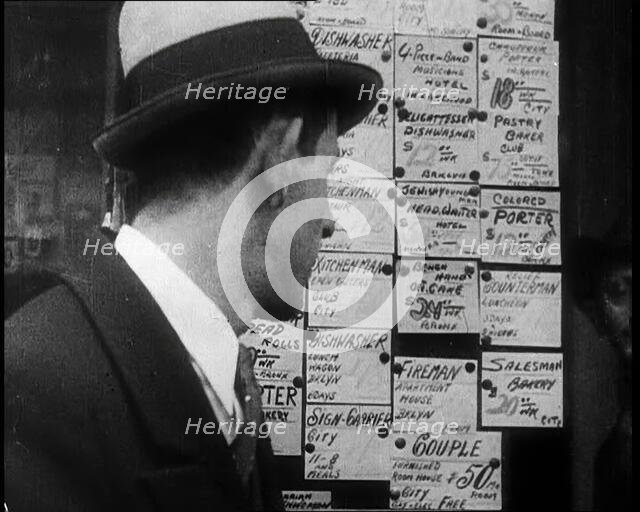 A Male Civilian Looking at a Board With Job Advertisements, 1932. Creator: British Pathe Ltd.