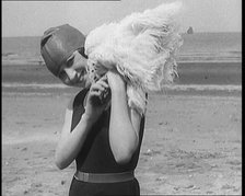 Female Civilian Wearing a Swimsuit Holding a Feathered Parasol at the Beach, 1920. Creator: British Pathe Ltd.