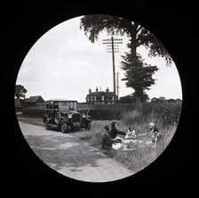 A group of women and girls having a picnic near a parked car at the side of a road..., 1920s-1930s. Creator: Norman Kingsley Harrison.