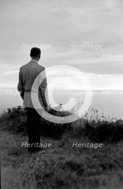 The silhouette of a man standing on a cliff top watching the sunset over the sea, c1945-c1965. Artist: SW Rawlings
