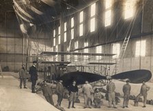 France. Hangar with the cockpit of an airship and a group of mechanics and pilots, 1900s.