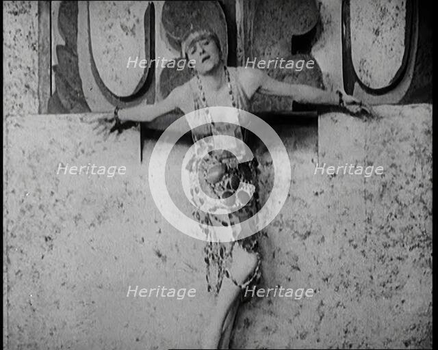 A Female Actor Chained to a Wall for a Performance, She Is Wearing a Glamorous Dress, 1922. Creator: British Pathe Ltd.