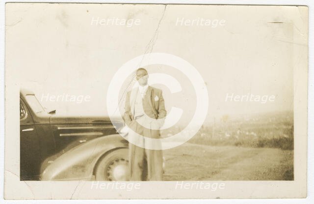 Photograph of an unidentified man in front of car, ca. 1920. Creator: Unknown.