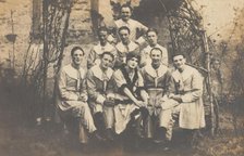 Concert party performers, one in drag, pose for a group portrait, (between 1910 and 1919?). Creator: Unknown.