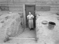Mrs. Free in doorway of her basement dugout home, Dead Ox Flat, Oregon, 1939. Creator: Dorothea Lange.