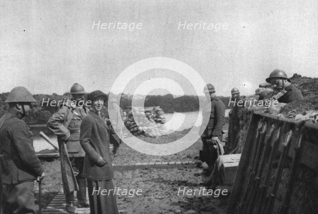 'La Reine des Belges sur les lignes de L'Yser; Un soldat (a droite) joue un air de violon', 1916. Creator: Unknown.