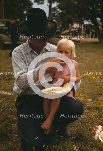 Homesteader feeding his daughter at the Pie Town, New Mexico Fair free barbeque, 1940. Creator: Russell Lee.