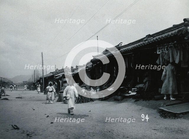 A line of shops beside a dusty street, with telegraph poles overhead, in Korea, c1900. Creator: Unknown.