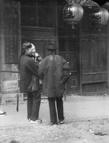 Two men, one holding a child, standing in the street, Chinatown, San Francisco, c1896-1906. Creator: Arnold Genthe.
