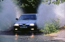 1989 Alfa Romeo 164 driving through a ford. Artist: Unknown.