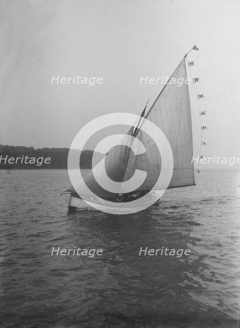 The sailing dinghy 'Hound' with flags, 1912. Creator: Kirk & Sons of Cowes.