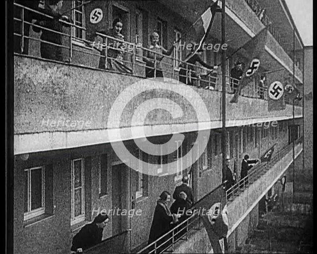 People Waving Flags of the Nazi Party and German Flags of 1867-1918 from Balconies, 1933. Creator: British Pathe Ltd.