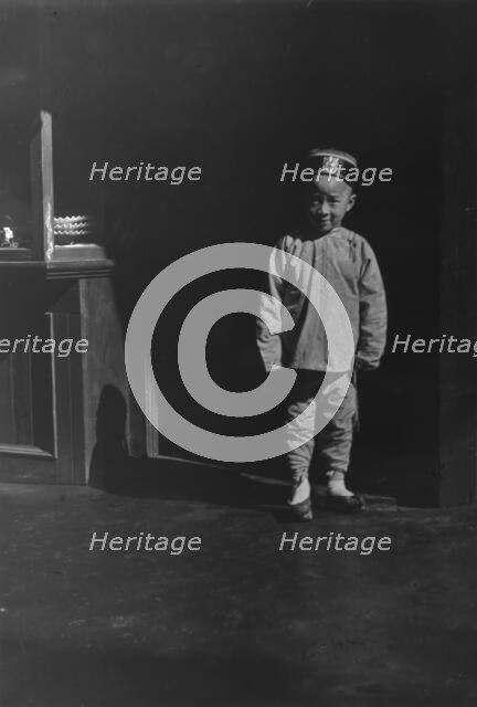 Boy in doorway of lamp store, Chinatown, San Francisco, between 1896 and 1906. Creator: Arnold Genthe.