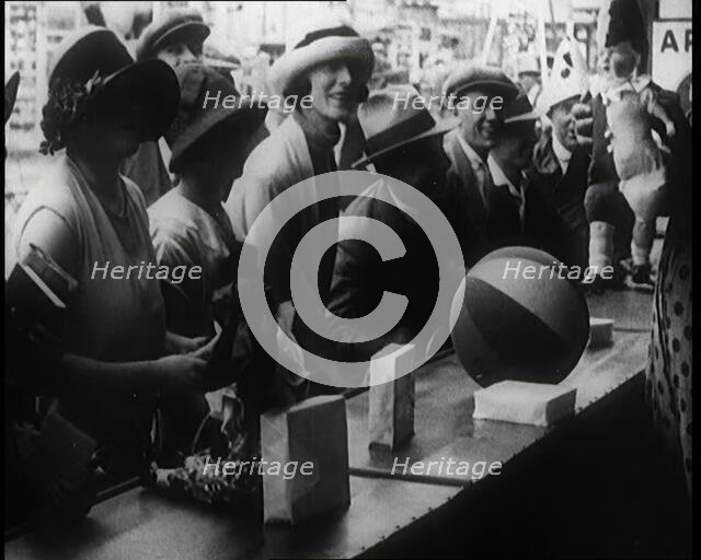 A Crowd of People Playing a Game Where They Have to Pop a Balloon By Turning a Handle, 1924. Creator: British Pathe Ltd.