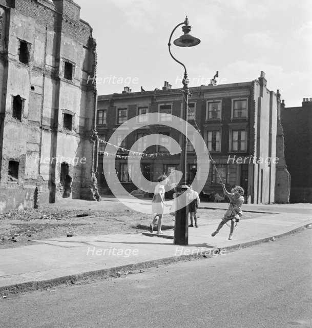 Children swinging on a lamppost, London, 1960-1965. Artist: John Gay