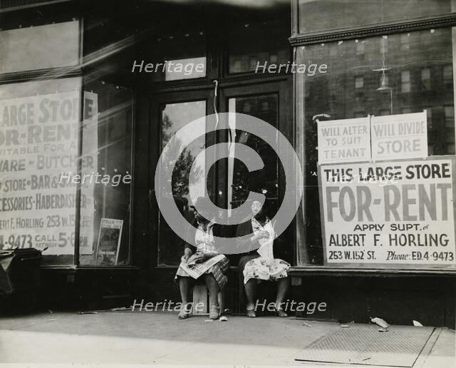 Sidewalk sitters. Two women sitting in doorway of empty storefront that is being..., ca. 1930s. Creator: Unknown.