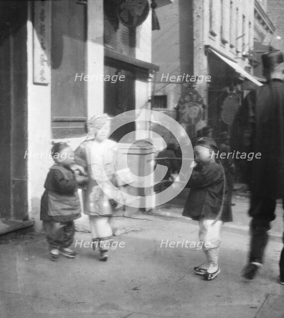 Three children standing on a sidewalk, Chinatown, San Francisco, between 1896 and 1906. Creator: Arnold Genthe.