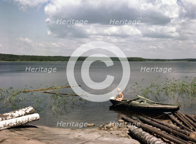 A boy fishing from a rowing boat during his summer holidays, Sweden, 1950s. Artist: Göran Algård