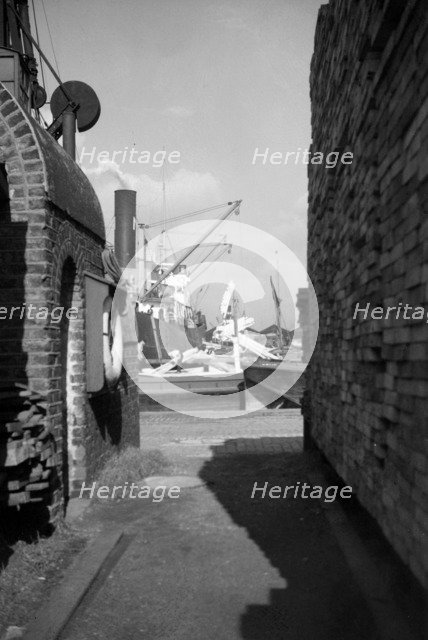 A view between harbour buildings in London docks, 1937. Artist: SW Rawlings