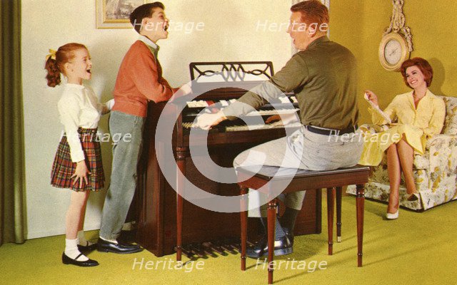 Family singing around a Wurlitizer organ as father plays, De Kalb, Illinois, USA, 1962. Artist: Unknown