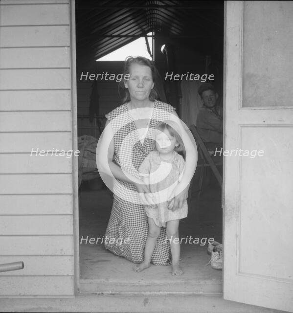 Migrant mother and child at doorway of steel shelter, FSA camp, Tulare County, 1939. Creator: Dorothea Lange.