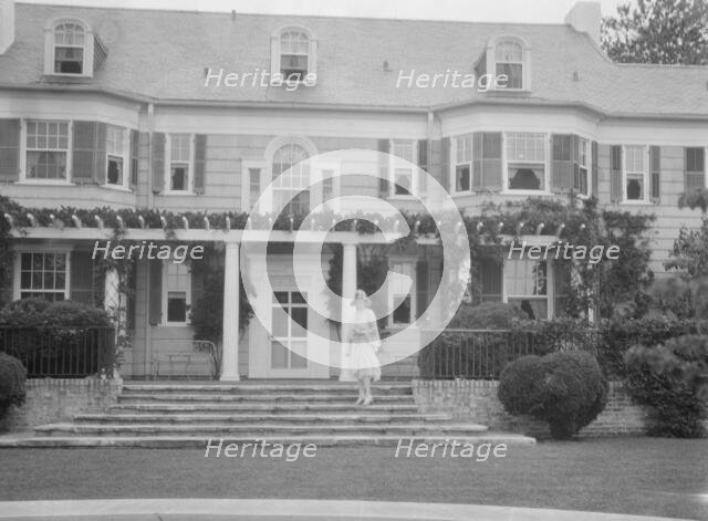 Gossler, Philip, Mrs., standing in front of residence, between 1927 and 1929. Creator: Arnold Genthe.