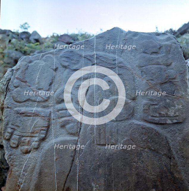 Detail of a sculptural relief on a rock representing a man with a large earring, at his left the …