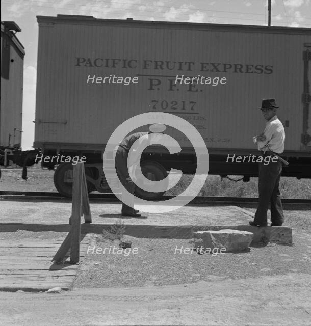 Inspecting a freight train from Mexico for smuggled immigrants, El Paso, Texas, 1938. Creator: Dorothea Lange.