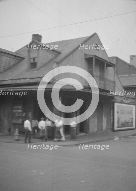 View from across street of a group of men on a street corner, New Orleans, between 1920 and 1926. Creator: Arnold Genthe.