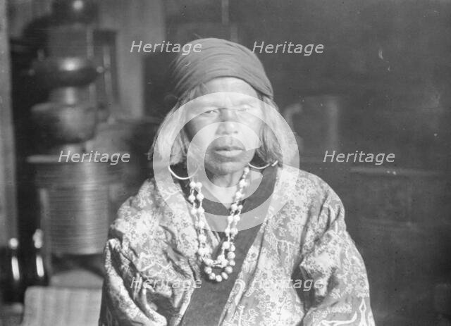 Ainu woman wearing a headscarf, earrings, and a necklace, 1908. Creator: Arnold Genthe.