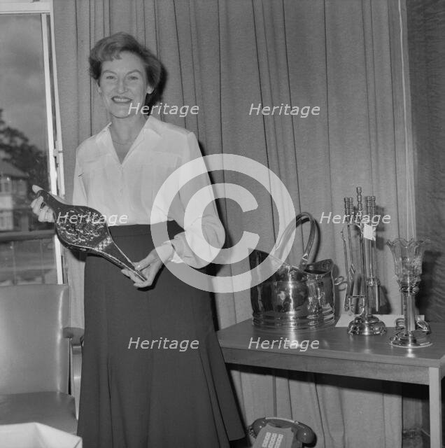 Mary Coldicott holding a brass ornamental gift, during her retirement presentation

, 01/08/1986. Creator: John Laing plc.