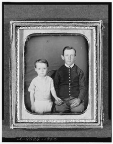 Unidentified boy seated in chair with child standing to left, three-quarter..., between 1850 & 1860. Creator: Unknown.