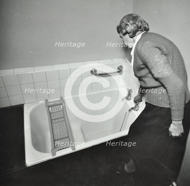 16 Candy Street, Poplar, London: elderly woman in bathroom, 1962. Creator: Unknown.