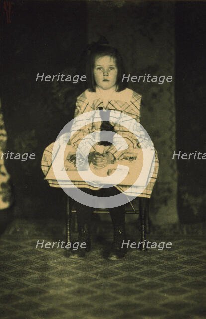 Girl in a plaid dress seated with a book in her lap, c1900. Creator: Mathilde Weil.