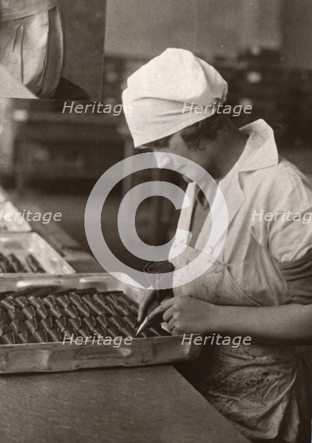 A woman uses a piping bag to decorate chocolates, Rowntree factory, York, Yorkshire, 1932. Artist: Unknown