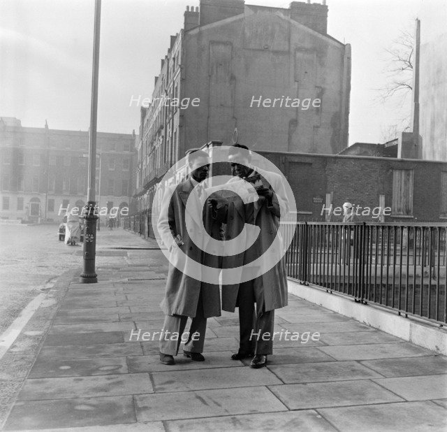 Two Afro-Caribbean men reading a map in the street, London, (c1950s?).   Creator: Henry Grant.
