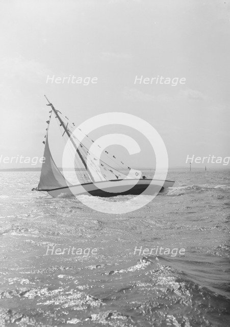The 7 Metre 'Ginerva' (K7) under sail with prize flags, 1912. Creator: Kirk & Sons of Cowes.